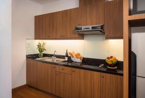 a kitchen with wooden cabinets and a sink with a bowl of fruit at Mercure Yangon Kaba Aye in Yangon
