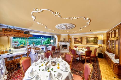 un restaurant avec des tables et des chaises blanches et un lustre dans l'établissement Hotel Irmchen, à Maintal