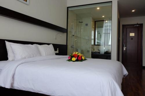 a white bed with a bouquet of flowers on it at Indochine Hotel in Kon Tum
