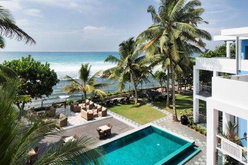 an aerial view of a resort with a swimming pool and the ocean at Owl and the Pussycat Hotel & Restaurant in Unawatuna