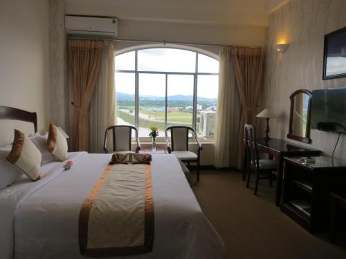 a hotel room with a bed and a large window at Indochine Hotel in Kon Tum