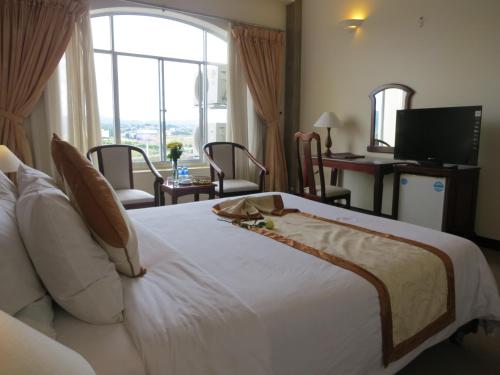 a bedroom with a large white bed with a large window at Indochine Hotel in Kon Tum