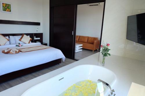 a bedroom with a tub and a bed and a television at Indochine Hotel in Kon Tum