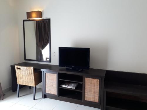 a black dresser with a television and a mirror at Gold Coast Morib Resort in Banting