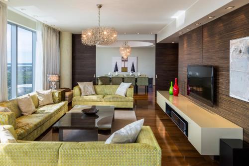 a living room with yellow couches and a tv at Swissotel Tallinn in Tallinn