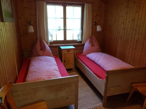 two beds in a small room with a window at Ferienhaus Stutz links in Küblis