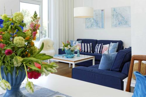 a living room with blue couches and a table with flowers at Kapitaensweg 4 Koje 03 in Karlshagen