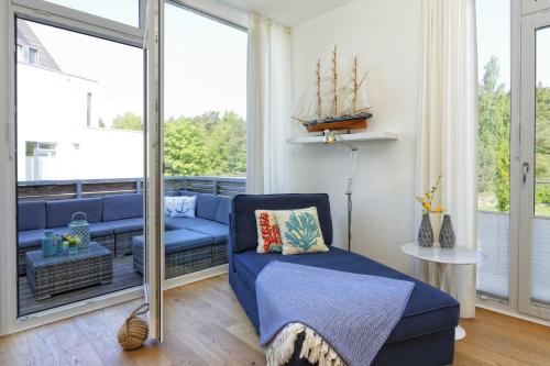 a living room with a blue couch and a large window at Kapitaensweg 4 Koje 03 in Karlshagen