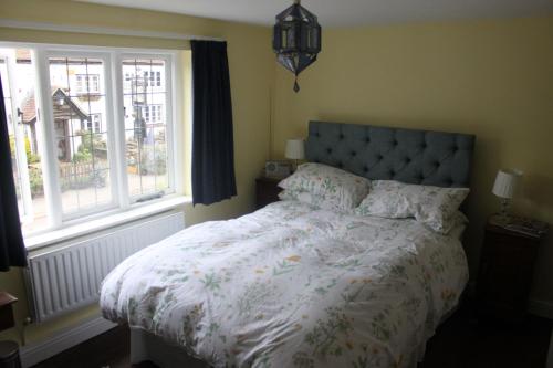 a bedroom with a bed with a floral comforter and two windows at IVY COTTAGE B and B in Buckingham