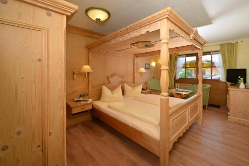 a bedroom with a canopy bed and a television at Sonnhof's Ferienresidenz in Reit im Winkl