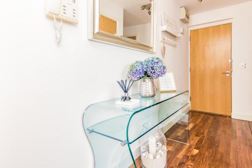 a glass table in a room with a vase of flowers at Oxfordshire Living - The Monroe Apartment - Oxford in Oxford