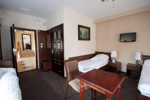 pokój hotelowy z 2 łóżkami i stołem w obiekcie Noclegi Nad Osławą w mieście Zagórz