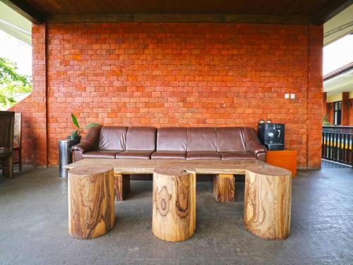 a brown leather couch sitting in front of a brick wall at Villa Gardenia Bandung in Lembang