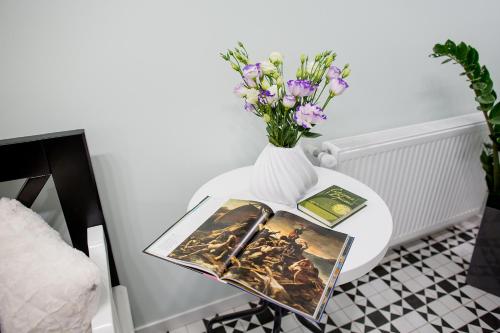 a table with a vase with flowers and a book at Art Deco Central Rooms in Lviv