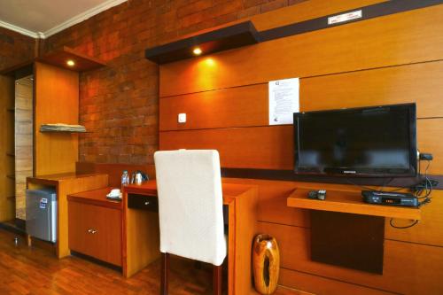 a living room with a tv and a white chair at Villa Gardenia Bandung in Lembang