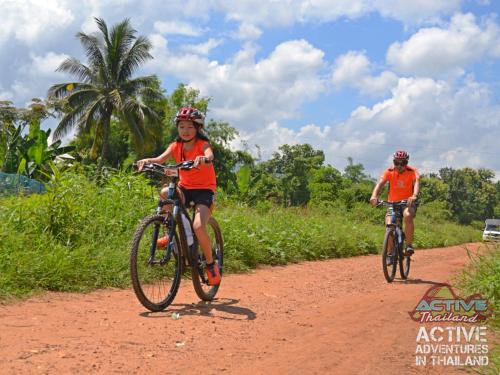 two people riding bikes on a dirt road at Le Cocotier in Ban Cho Lae