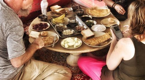 een groep mensen die rond een tafel zitten met eten bij Desert Haveli Guest House in Jaisalmer