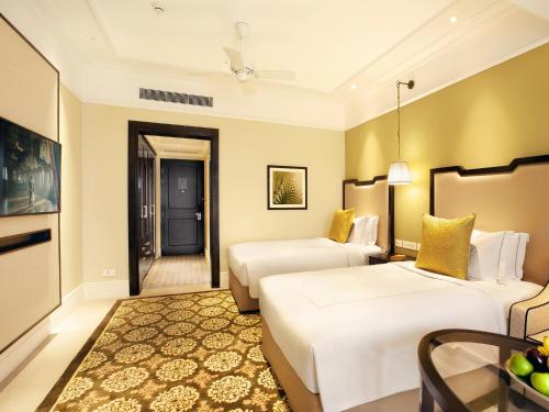 a hotel room with two beds and a table at Taj Connemara, Chennai in Chennai