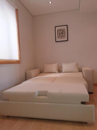 a white bedroom with a bed in a room at Casa Picadeiro in Figueira da Foz