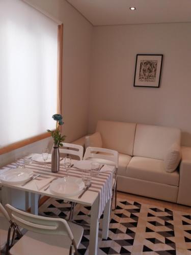 a dining room with a table and chairs and a couch at Casa Picadeiro in Figueira da Foz