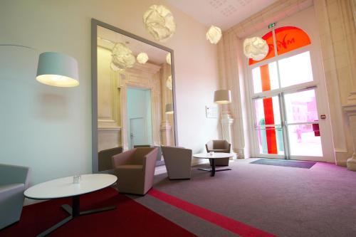 a lobby with chairs and tables and a large mirror at Mercure Cholet Centre in Cholet
