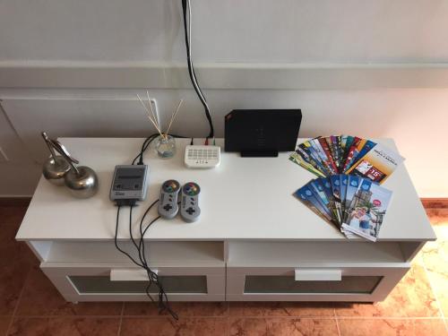 een wit bureau met 2 afstandsbedieningen en een laptop bij Apartamento Allegra in Arinaga