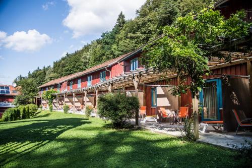 a building with a grass yard next to a mountain at JUFA Hotel Bruck an der Mur - im Weitental in Bruck an der Mur
