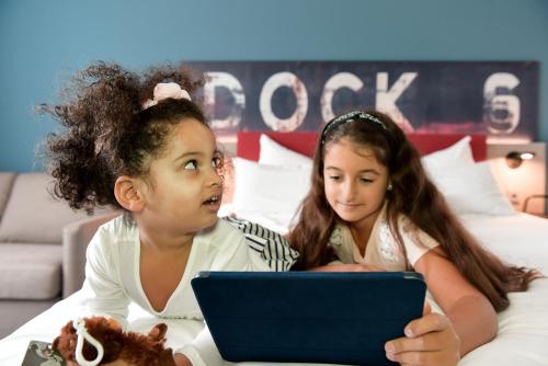 two young girls laying on a bed with a laptop at Mercure Hotel Hamburg City in Hamburg