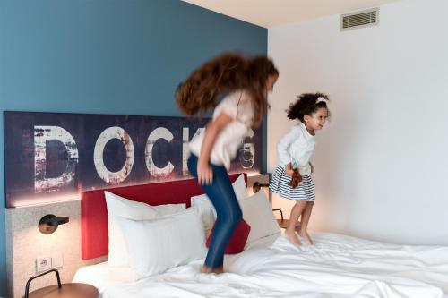 two girls jumping on a bed in a hotel room at Mercure Hotel Hamburg City in Hamburg