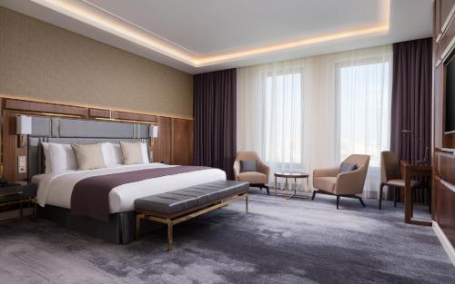 サマラにあるLotte Hotel Samaraのベッド、テーブル、椅子が備わるホテルルームです。