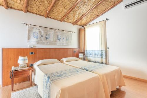 a bedroom with two beds and a table with a lamp at Hotel Villa Canu in Càbras