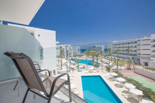 a balcony with a pool and chairs and a swimming pool at Tsokkos Protaras Beach Hotel in Protaras