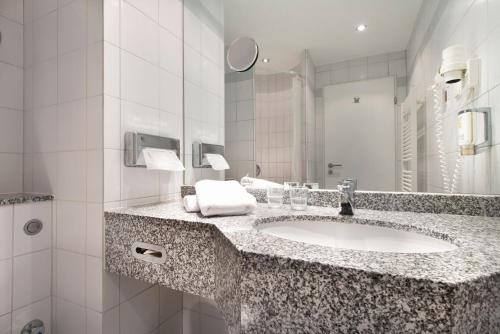 a bathroom with a sink and a mirror at SORAT Hotel Cottbus in Cottbus