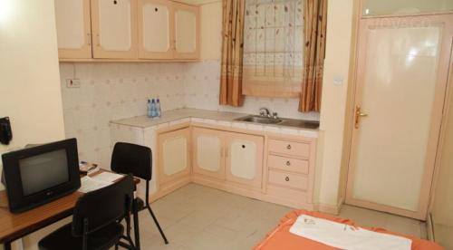 a kitchen with a desk and a tv in a room at Adventist LMS Guest House & Conference Centre in Nairobi