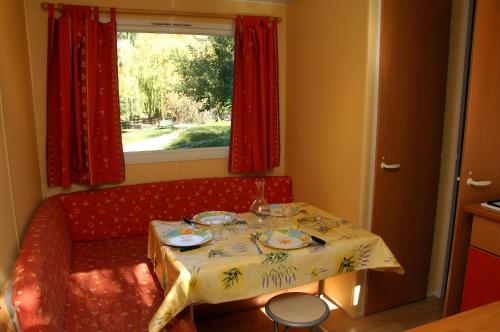 a small table with a red couch and a window at Camping La Ferme de Castellane in Castellane