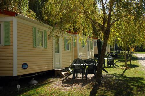 a yellow house with two chairs and a tree at Camping La Ferme de Castellane in Castellane
