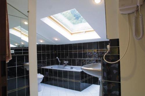 a bathroom with a skylight and a tub and a sink at La Fischhutte, The Originals Relais (Relais du Silence) in Mollkirch