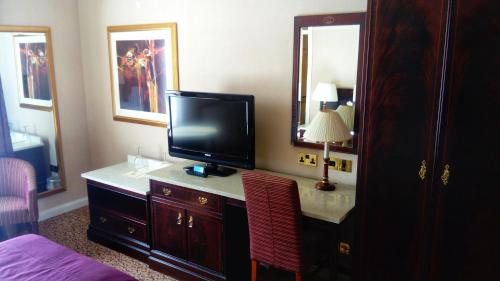 a hotel room with a television on a dresser at Shrigley Hall Hotel in Macclesfield