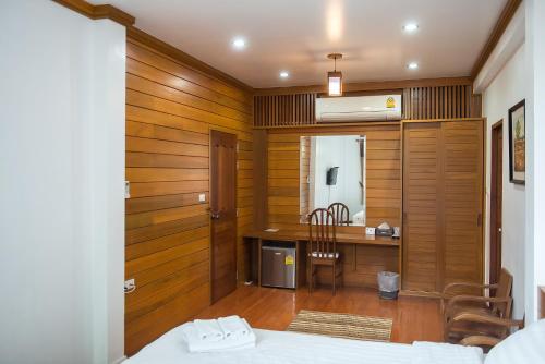 Tree Home Plus في ناخون سي ثامارات: غرفة نوم بجدران خشبية ومكتب وسرير