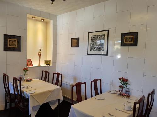 a dining room with two tables and chairs with white walls at Alba Guest House in Aberdeen