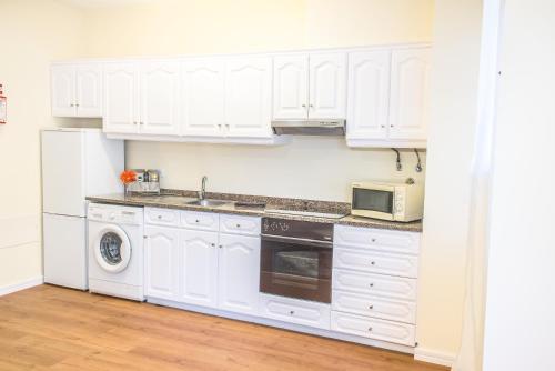 
a kitchen with white cabinets and white appliances at Arcadas Cozy Apartments - AV in Funchal
