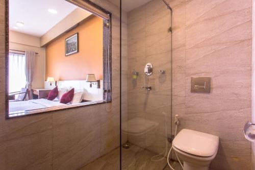 a bathroom with a shower and a toilet and a bedroom at Hotel Queens Park in Pokhara