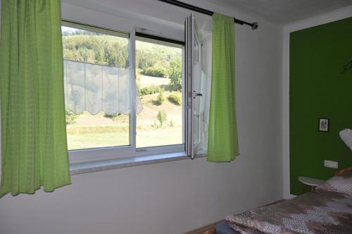 a bedroom with a window with green curtains at Ferienhaus Steyrdurchbruch in Leonstein