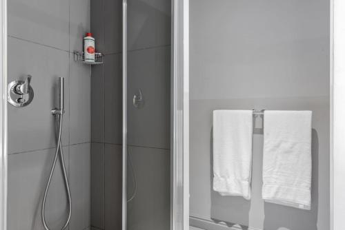 a bathroom with a shower with a glass door and white towels at Palazzo Cambiaso in Genoa
