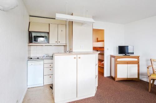 Una cocina con gabinetes blancos y un microondas. en Residence Les Tamaris - maeva Home, en Trouville-sur-Mer