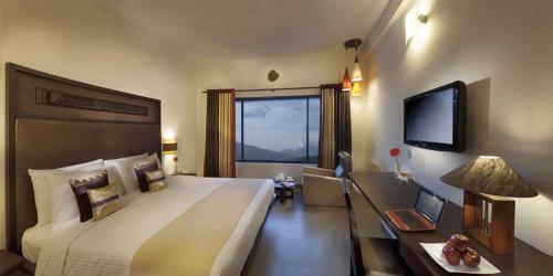 a hotel room with a large bed and a television at Sterling Munnar in Munnar
