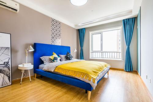 ein Schlafzimmer mit einem blauen Bett und einem Fenster in der Unterkunft Qingdao Shibei·Qingdao Wanda Plaza· Locals Apartment 00166560 in Qingdao