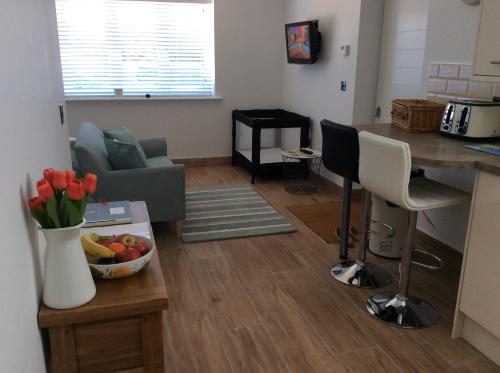 a living room with a couch and a table with a bowl of fruit at Cliff Top Studio in Barton on Sea