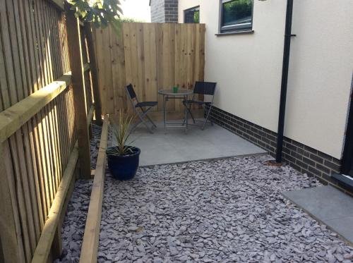 a patio with a table and chairs next to a fence at Cliff Top Studio in Barton on Sea