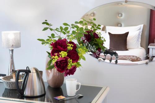 a vase of flowers on a table in a bedroom at Hotel Plaza Elysées in Paris